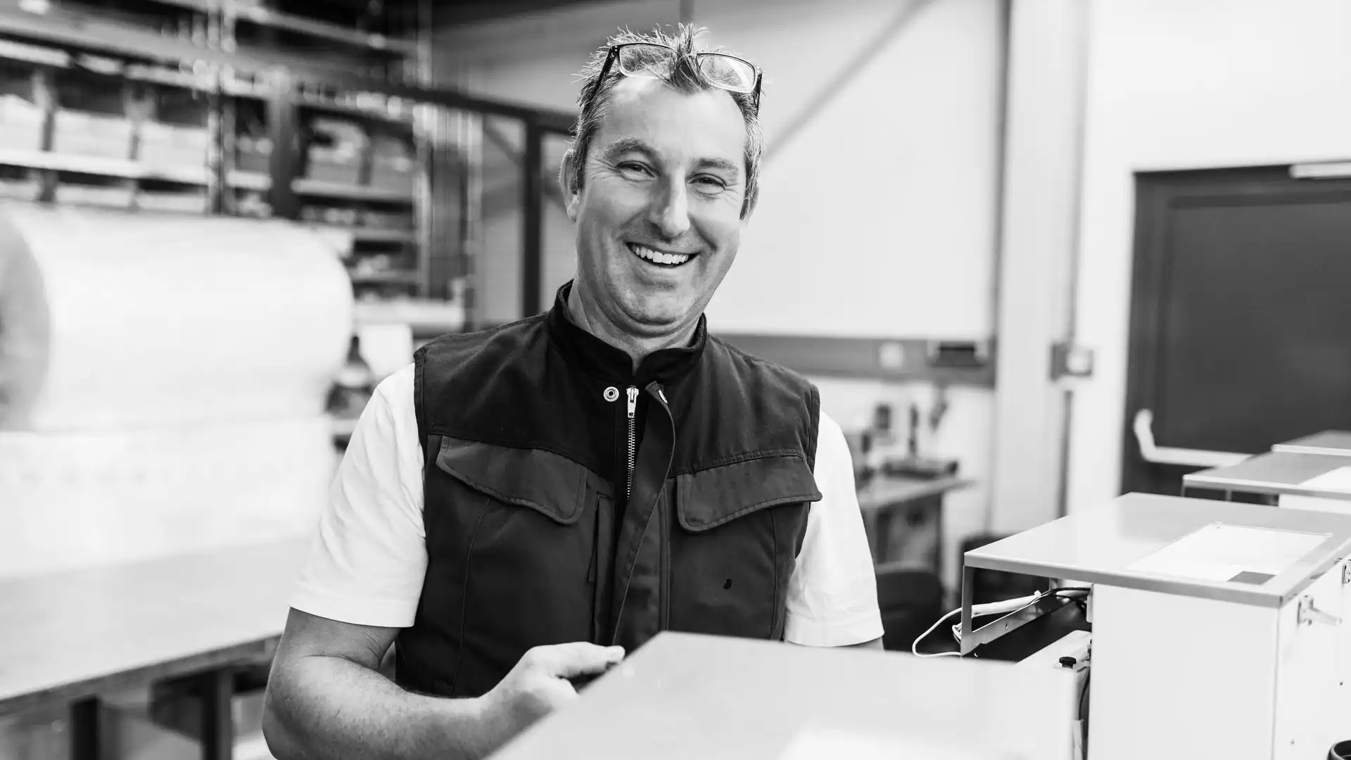 Lächelnder Mitarbeiter in der Werkstatt von Feinwerk Hamburg beim Zusammenbau von Geräten